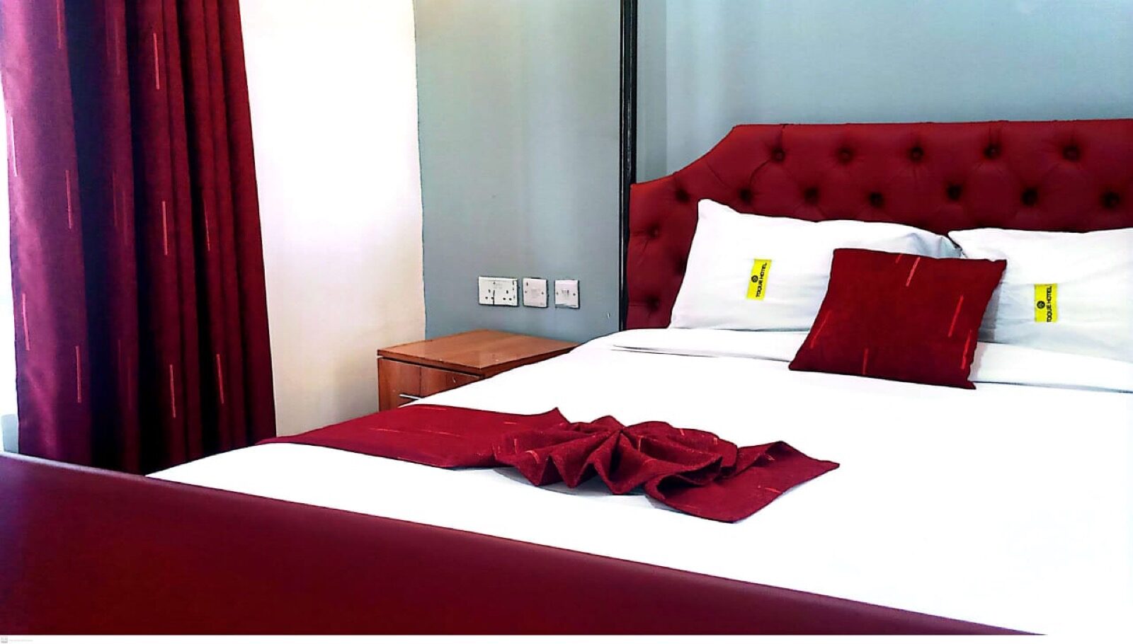 Clean guest room at Toque Hotel Nairobi with burgundy headboard